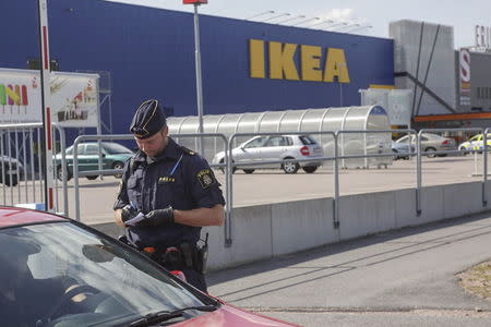 A police officer writes on a notepad as he speaks to a driver near an Ikea store in Vasteras, central Sweden, August 10, 2015. REUTERS/Peter Kruger/TT News Agency