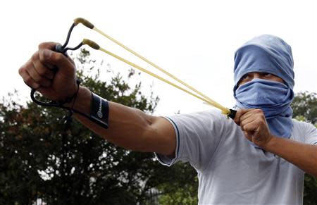 A demonstrator uses a slingshot against the National Guard during a protest against Venezuelan President Nicolas Maduro's government in San Cristobal, about 410 miles (660 km) southwest of Caracas, February 27, 2014. REUTERS/Carlos Garcia Rawlins