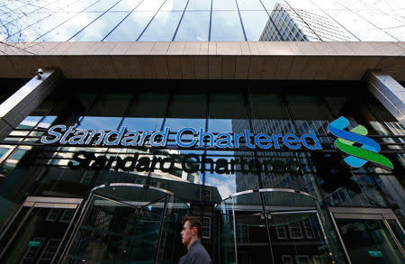 A man walks past the head office of Standard Chartered bank in the City of London February 27, 2015. REUTERS/Eddie Keogh