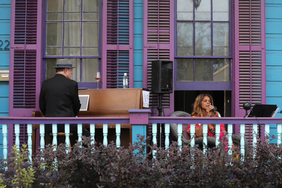 Anais St. John and pianist Harry Mayronne hold a front porch concert at her home in New Orleans, Saturday, April 11, 2020. With New Orleans music venues shuttered for more than a month now because of the coronavirus outbreak, musicians and fans are finding new places to connect – porches, living rooms, studios and lawns – and reaching their largest audiences online, many streaming performances live on social media platforms. But for the city's club owners awaiting the green light to reopen there's concern about all the uncertainties, like how long it may take tourists to return, how soon the music scene will rebound and when it does, what it will look like. (AP Photo/Gerald Herbert)