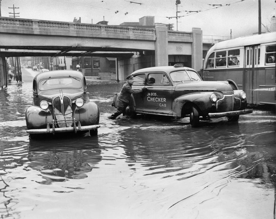 March 8, 1945. Photo by Art Abfier. One car abandoned, second rescued under new Baxter Ave. overpass. Today for the first time since 1937, Beargrass Creek was over teh street bridge at Baxter Ave., flooding the L&N underpass. Photographed at 7:30am, Jefferson-Bardstown buses could still pass, but one car is shown stalled while Raymond Newman, 1031 E. Jefferson, helped rescuea drowned-out taxi. In 1937, it was the site of the whisky barrel pontoon bridge with water up to the rail elevation.