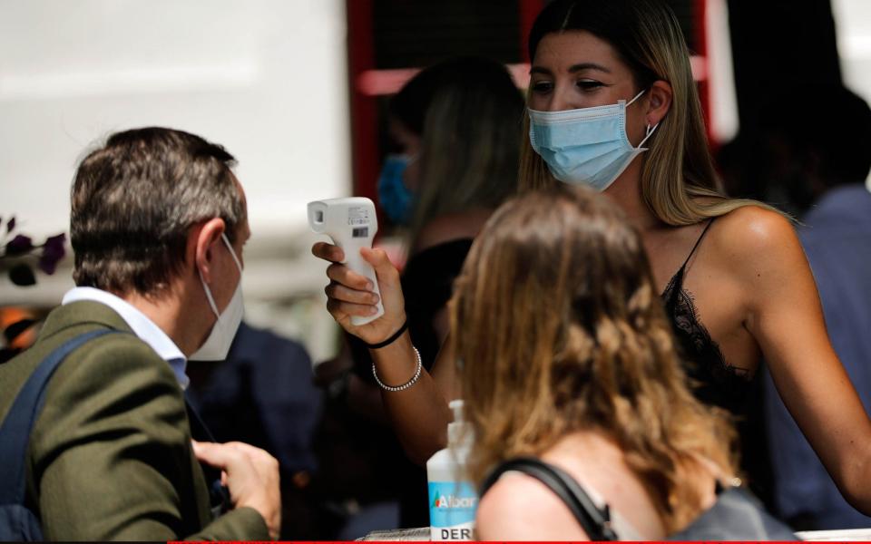 A cafe worker checks body temperature of client as side-walk restaurants, cafes and bars are allowed to open after 9 weeks of severe lockdown  -  Anadolu Agency/ Anadolu 