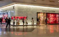 Patrons stand in a line to enter the Louis Vuitton shop at the upmarket shopping mall Siam Paragon in Bangkok, Thailand, Sunday, May 17, 2020. Thai authorities allowed department stores, shopping malls and other businesses to reopen from Sunday, selectively easing restrictions meant to combat the coronavirus. (AP Photo/ Gemunu Amarasinghe)