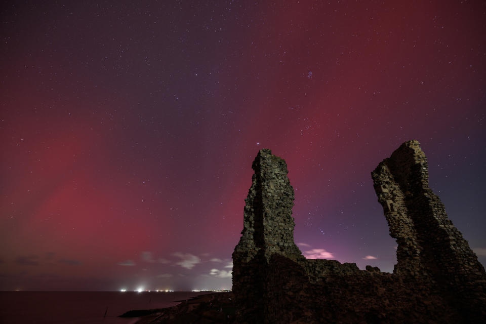 Ruins silhouetted against a starry night sky with a red aurora, creating a dramatic landscape