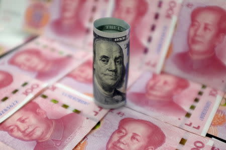 Benjamin Franklin U.S. 100-dollar banknote and Chinese 100-yuan banknotes depicting the late Chinese Chairman Mao Zedong, are seen in a picture illustration in Beijing, China, January 21, 2016. REUTERS/Jason Lee/File Photo