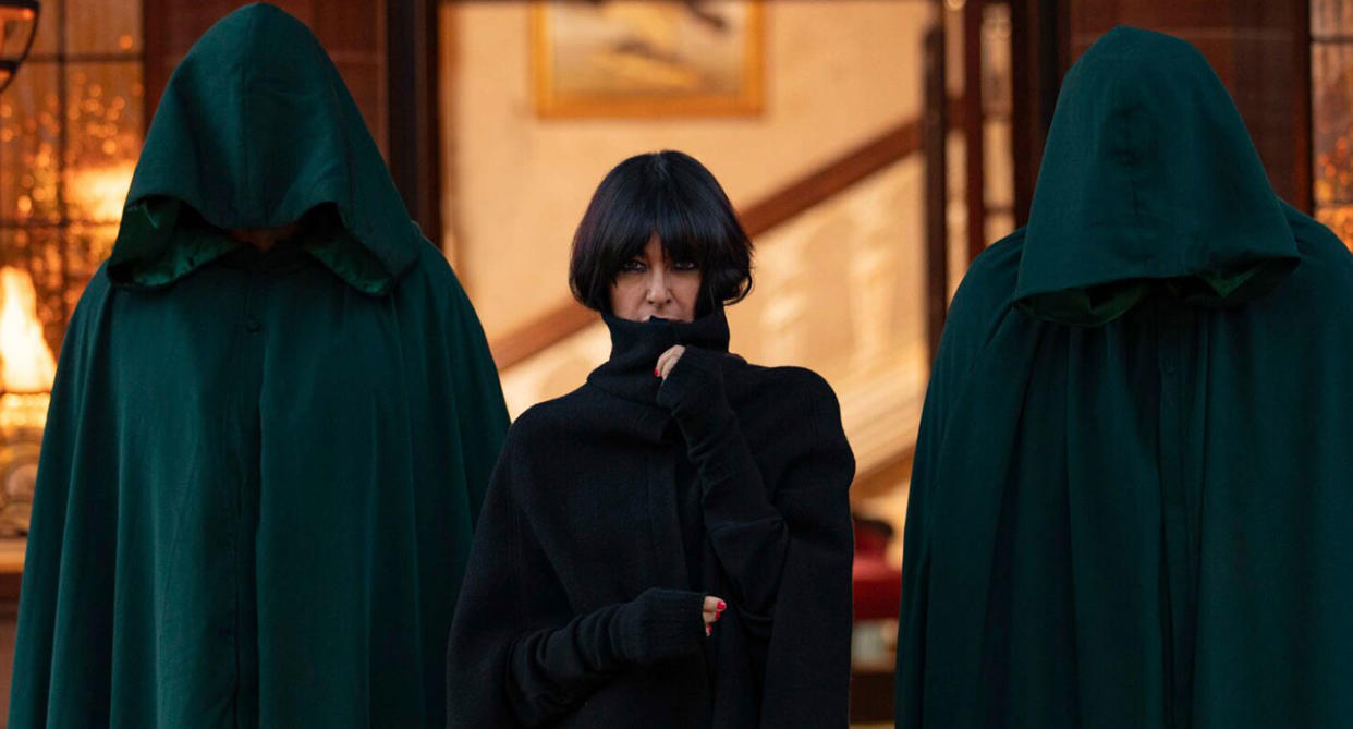 Claudia Winkleman stood with two cloaked figures from The Traitors
