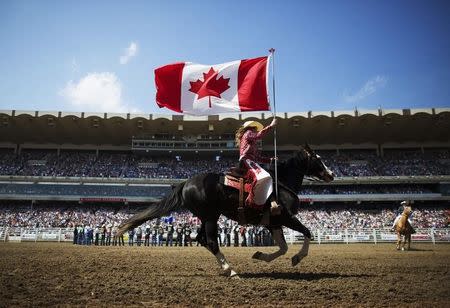 A Calgary Stampede rodeo girl carries the Canadian flag during the singing of the national anthem during day 2 of the Calgary Stampede rodeo in Calgary, Alberta, July 5, 2014. REUTERS/Todd Korol