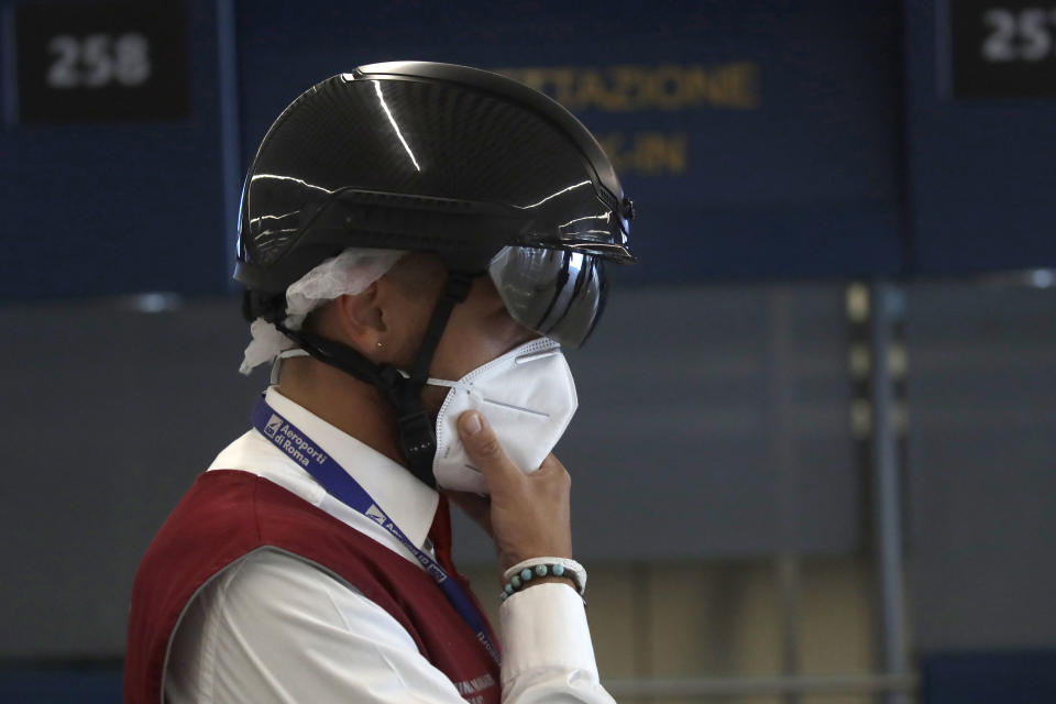 An airport security member wears a smart helmet scanner which measures the body temperature of passengers for possible coronavirus symptoms, Rome's Fiumicino airport, Wednesday, June 3, 2020. Rome’s Fiumicino airport sprang back to life on Wednesday as Italy opened regional and international borders in the final phase of easing its long coronavirus lockdown, allowing families and loved ones separated by the global pandemic to finally reunite. (AP Photo/Alessandra Tarantino)