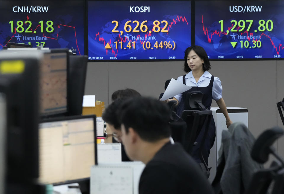 A currency trader walks by screens showing the Korea Composite Stock Price Index (KOSPI), top center, and the foreign exchange rate between U.S. dollar and South Korean won, top right, at the foreign exchange dealing room of the KEB Hana Bank headquarters in Seoul, South Korea, Wednesday, June 7, 2023. Asian shares were mixed Wednesday after a day of listless trading on Wall Street in the absence of market-moving data.(AP Photo/Ahn Young-joon)