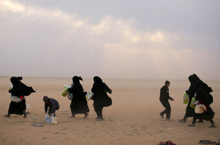 Women walk with their belongings near the village of Baghouz, Deir Al Zor province, Syria February 26, 2019. REUTERS/Rodi Said