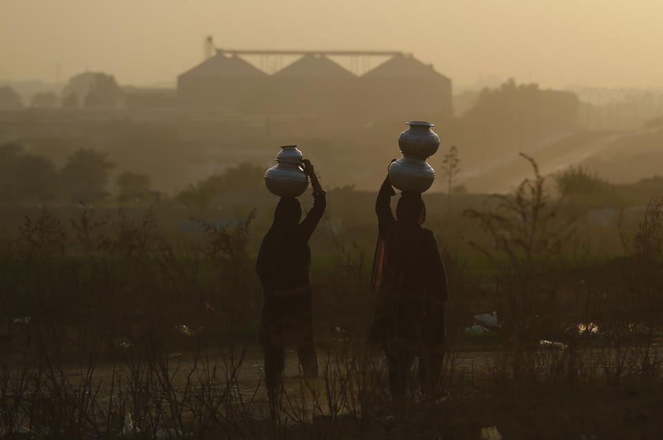 Pakistani nomad women carry water to their houses in a hazy evening on the outskirts of Islamabad, Pakistan, Tuesday, Dec. 4, 2018. The COP 24 UN Climate Change Conference is taking place in Katowice, Poland where negotiators from around the world are meeting for talks on curbing climate change. (AP Photo/Anjum Naveed)