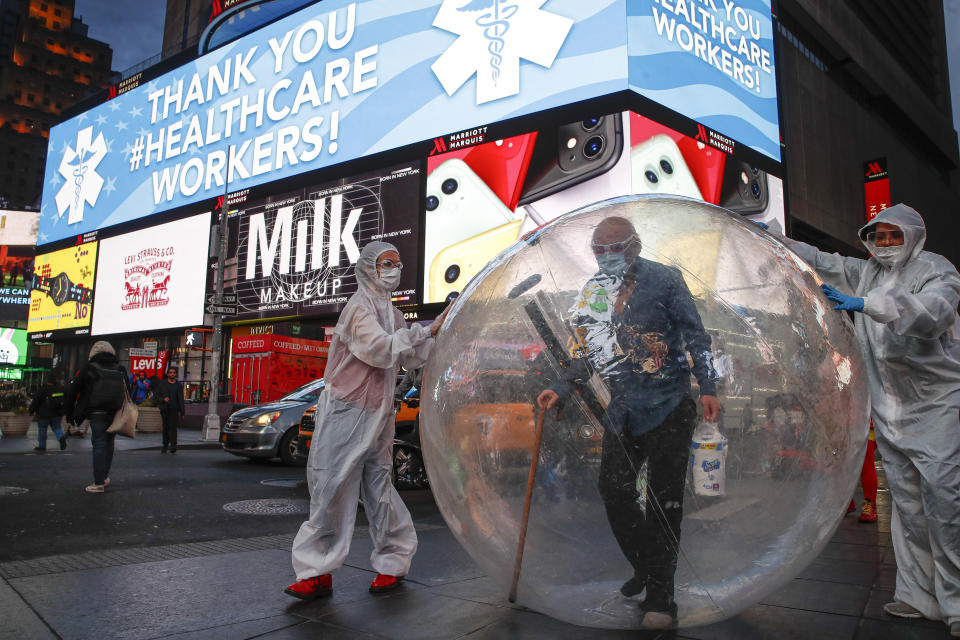 Artists perform under a billboard displaying thanks to healthcare workers due to COVID-19 concerns in a sparsely populated Times Square, Friday, March 20, 2020, in New York. New York Gov. Andrew Cuomo is ordering all workers in non-essential businesses to stay home and banning gatherings statewide. "Only essential businesses can have workers commuting to the job or on the job," Cuomo said of an executive order he will sign Friday. Nonessential gatherings of individuals of any size or for any reason are canceled or postponed. (AP Photo/John Minchillo)