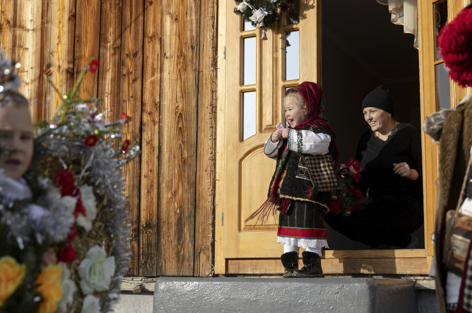 A girl, dressed in a traditional costume, reacts after being handed money as a gift while celebrating the Malanka festival in the village of Krasnoilsk, Ukraine, Thursday, Jan. 13, 2022. (AP Photo/Ethan Swope)