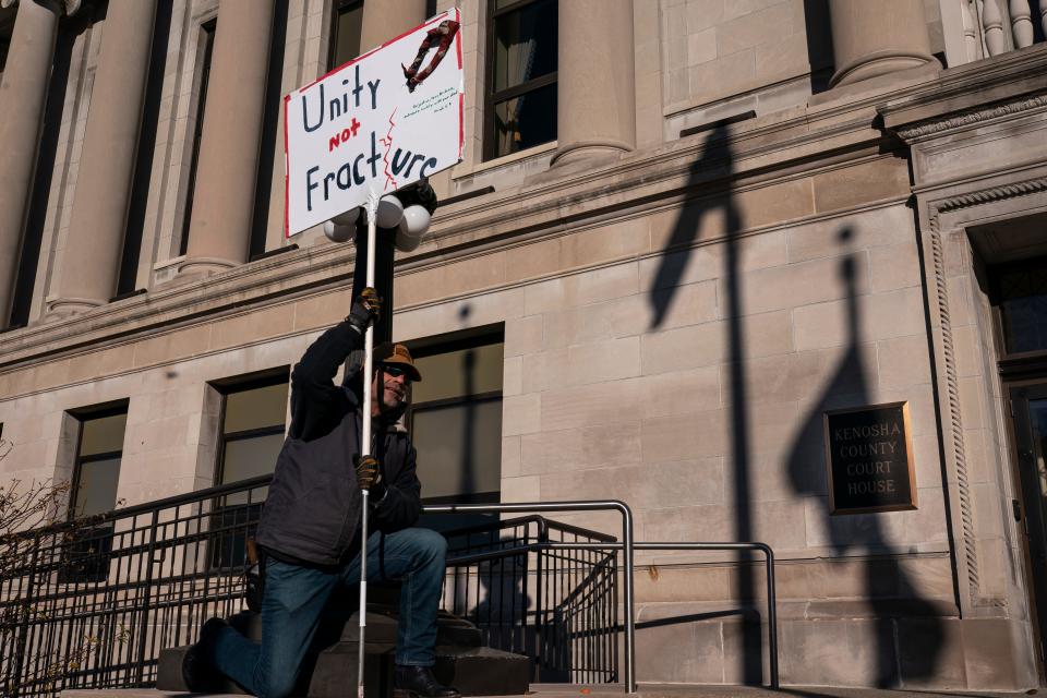 Dave Graham held a sign calling for national unity outside the Kenosha County (Wisconsin) Courthouse while the jury deliberated the Kyle Rittenhouse trial on Nov. 18.