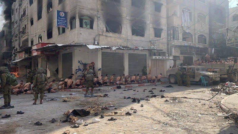 Captured and detained Palestinians sit on a street in Beit Lahia