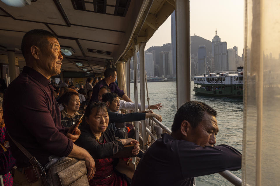 FILE - Mainland Chinese tourists ride the Star Ferry in Hong Kong, April 12, 2023. Living in Hong Kong today means juggling contradictory feelings. In 20 interviews, many said that when they focus on business indicators and everyday life, they see a recovery gathering pace after years of travel restrictions. But when it comes to anything political, the openness and freedoms that were once hallmarks of the Chinese-ruled former British colony seem permanently gone. (AP Photo/Louise Delmotte, File)