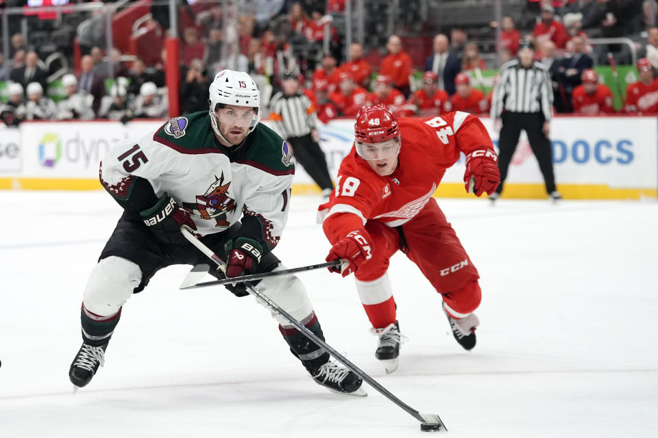 Arizona Coyotes center Alex Kerfoot (15) and Detroit Red Wings right wing Jonatan Berggren (48) reach for the puck during the first period of an NHL hockey game, Thursday, March 14, 2024, in Detroit. (AP Photo/Carlos Osorio)