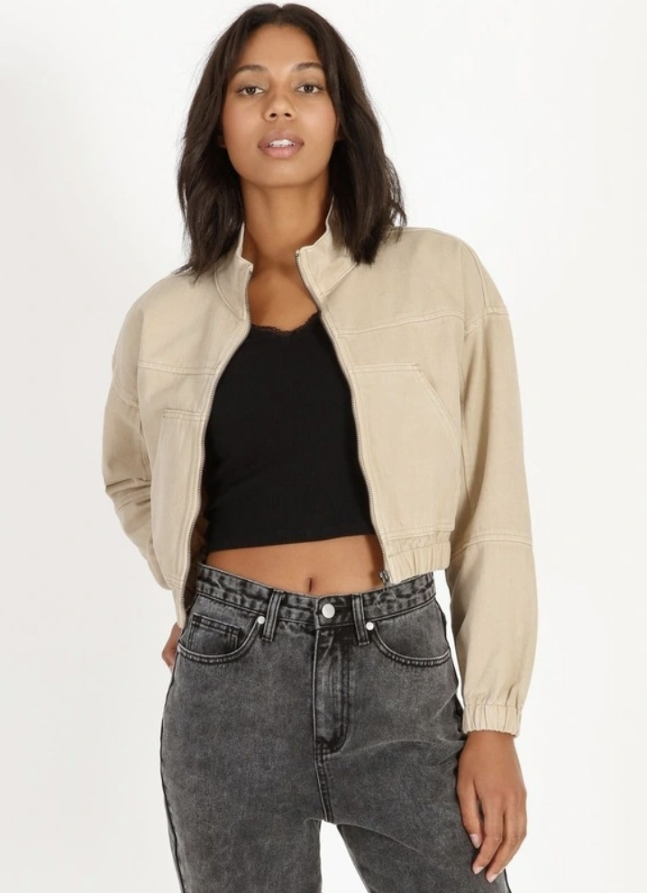 A woman with shoulder-length dark hair wears a beige Miss Shop Denim Bomber Jacket, $25, over black top and jeans.