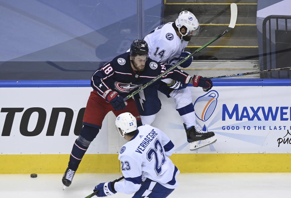 Columbus Blue Jackets center Pierre-Luc Dubois (18) hits Tampa Bay Lightning left wing Pat Maroon (14) along the boards during the third period of an NHL Eastern Conference Stanley Cup hockey playoff game in Toronto, Saturday, Aug. 15, 2020. (Nathan Denette/The Canadian Press via AP)
