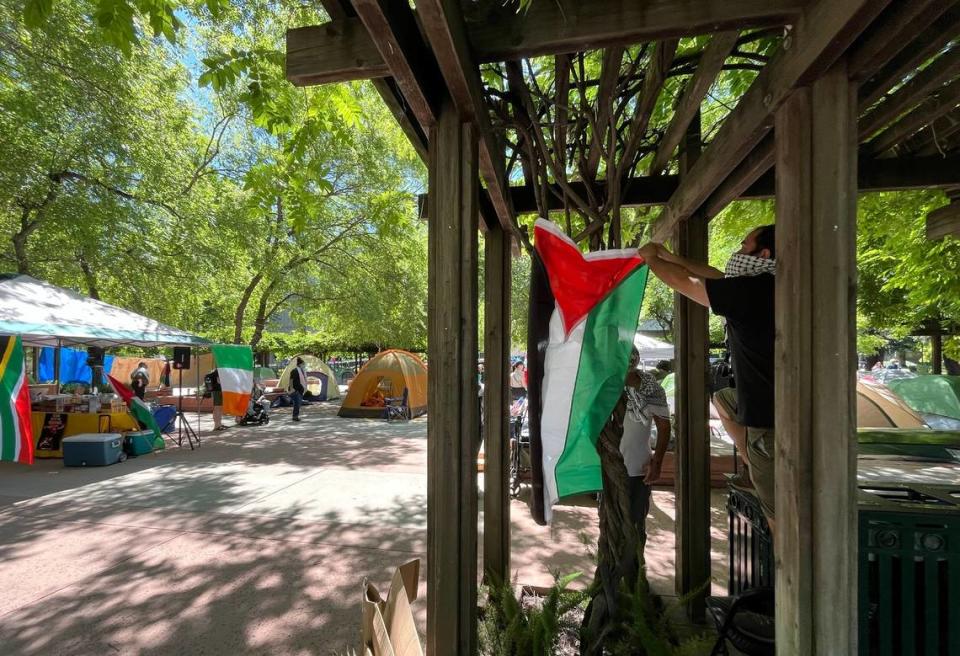 Activists hang a Palestinian flag on Monday at the entrance to an area at Sacramento State where tents were erected to protest the war in Gaza. Students are asking the university to divest from investments in Israel.