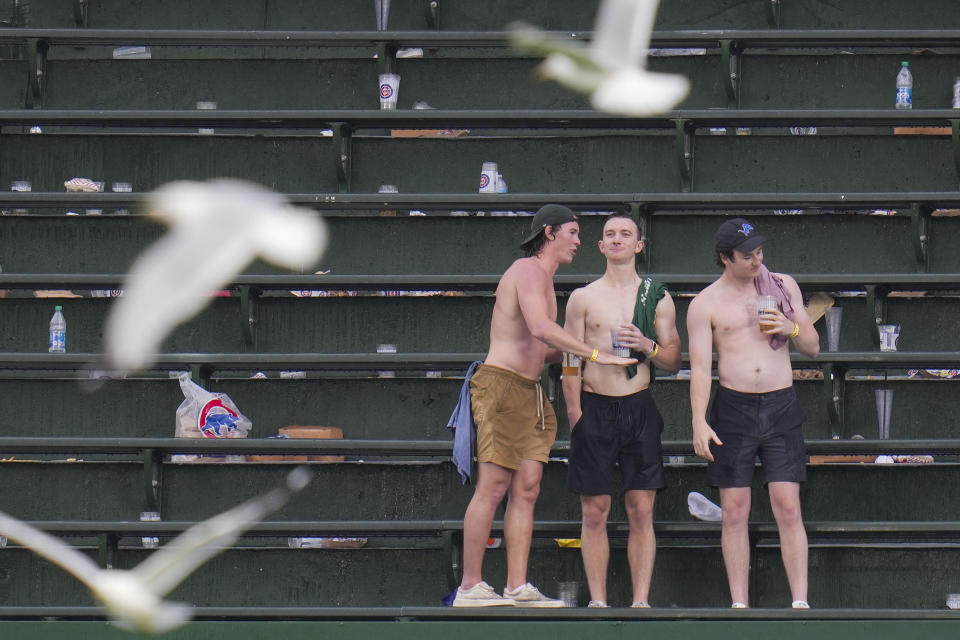 Shirtless fans stand in the bleachers during a second rain delay during the seventh inning of a baseball game between the St. Louis Cardinals and Chicago Cubs, Saturday, July 22, 2023, in Chicago. (AP Photo/Erin Hooley)