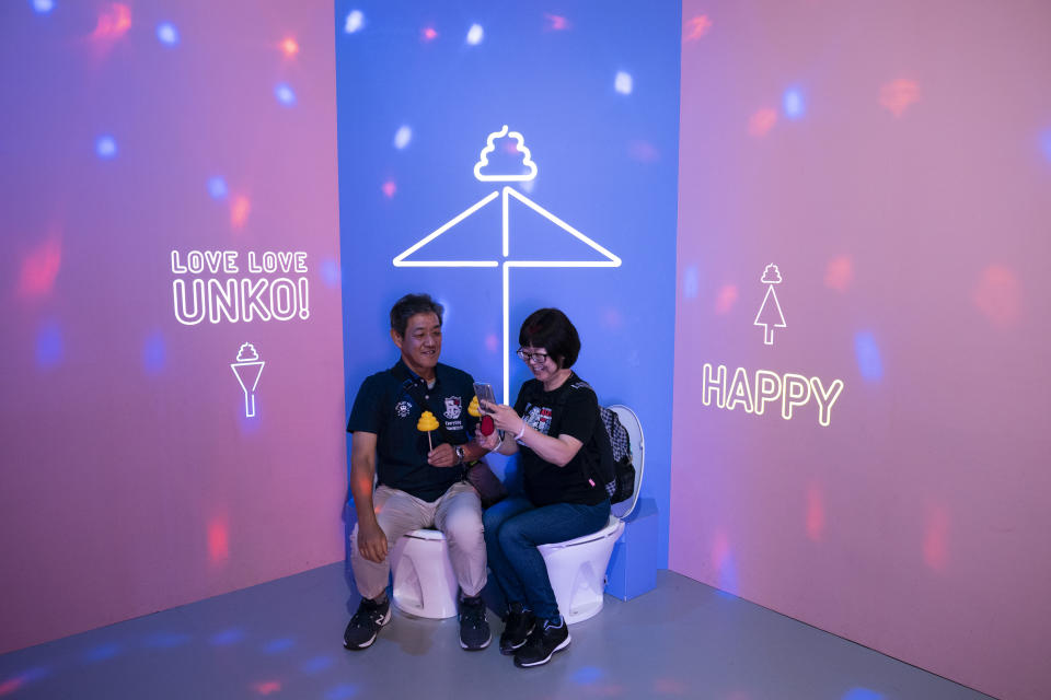 In this Tuesday, June 18, 2019, photo, a couple shares a light moment while sitting on toilet bowls at the Unko Museum in Yokohama, south of Tokyo. In a country known for its cult of cute, even poop is not an exception. A pop-up exhibition at the Unko Museum in the port city of Yokohama is all about unko, a Japanese word for poop. The poop installations there get their cutest makeovers. They come in the shape of soft cream, or cupcake toppings. (AP Photo/Jae C. Hong)