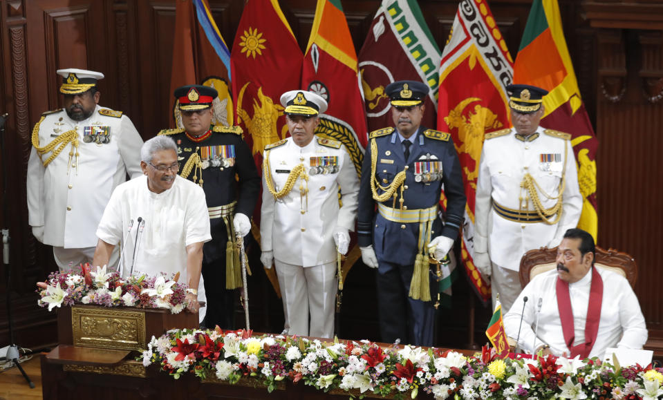 Sri Lankan President Gotabaya Rajapaksa speaks, watched by his brother and Prime Minister Mahinda Rajapaksa in Colombo, Sri Lanka, Friday, Nov. 22, 2019. Rajapaksa, who was elected last week, said he would call a parliamentary election as early as allowed. The parliamentary term ends next August, and the constitution allows the president to dissolve Parliament in March and go for an election. (AP Photo/Eranga Jayawardena)