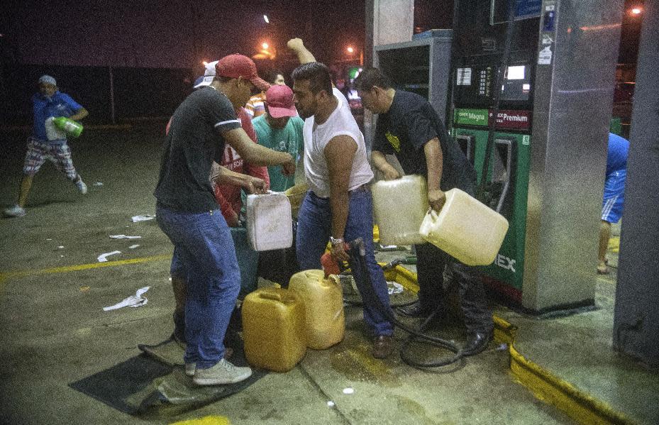 Residents pilfer gasoline and diesel from a gas station following protests against an increase in fuel prices in Allende, southern Veracuz State, Mexico, late Tuesday Jan. 3, 2017. The gas station attendants who had turned off the power to inactivate the pumps were intimidated by demonstrators into turning them back on, and allowing the residents to take the fuel. Nationwide protests continued as small groups shut down or looted gas stations and blocked roads to protest a price deregulation that has sent the cost of fuel up by as much as 20 percent. (AP Photo/Erick Herrera)