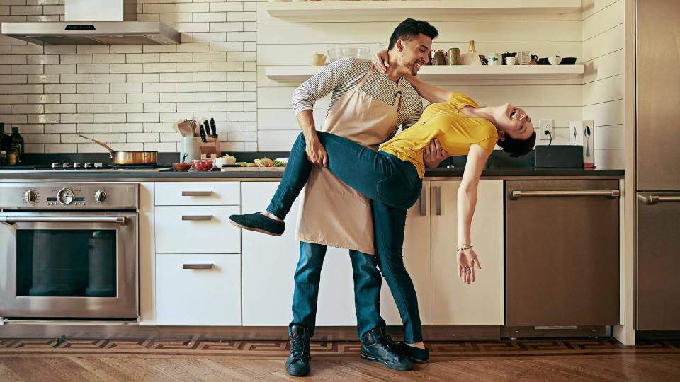 Shot of a young couple dancing in their kitchen.