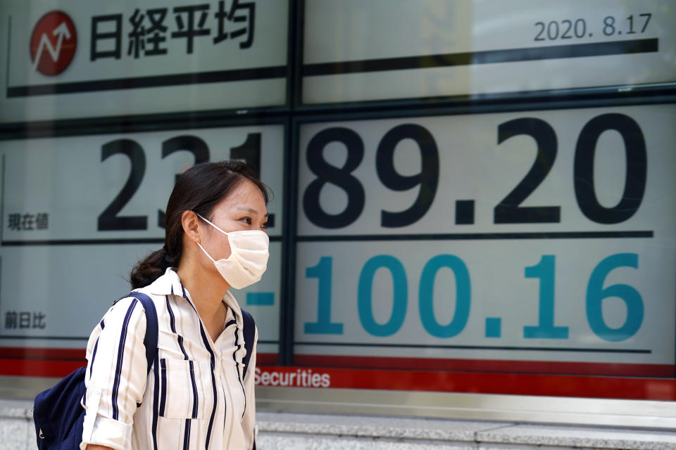 A woman walks past an electronic stock board showing Japan's Nikkei 225 index at a securities firm in Tokyo Monday, Aug. 17, 2020. Japanese stocks sank while other Asian markets gained Monday after Japan reported a record economic contraction as the coronavirus pandemic weighed on retailing, investment and exports. (AP Photo/Eugene Hoshiko)