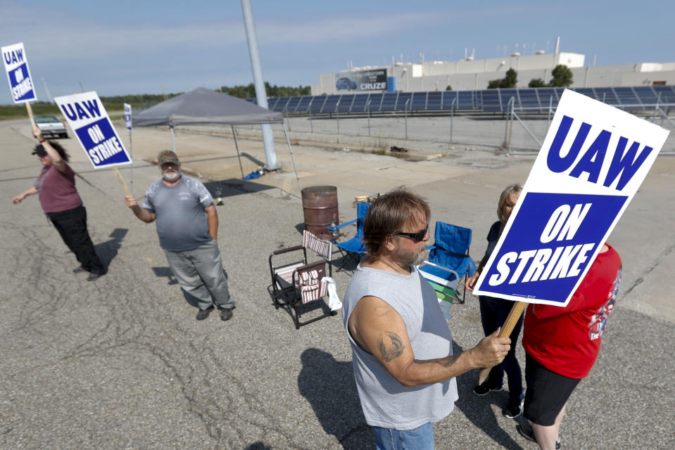 FILE - In this Sept. 16, 2019, file photo picketers carry signs at one of the gates outside the closed General Motors automobile assembly plant in Lordstown, Ohio. Many from Lordstown, Ohio, and near Baltimore and Detroit are opposing a deal that could end a 37-day strike that crippled GM’s U.S. production and cost the company an estimated $2 billion. (AP Photo/Keith Srakocic, File)