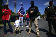 A boy carries a pro-Trump flag flanked by two security guards and his mother moments before leaving for the headquarters of the Republican party in support of President Donald Trump's candidacy a few weeks before the presidential election next November, in Carolina, Puerto Rico, Sunday, Oct. 18, 2020. President Donald Trump and former Vice President Joe Biden are targeting Puerto Rico in a way never seen before to gather the attention of tens of thousands of potential voters in the battleground state of Florida. (AP Photo/Carlos Giusti)