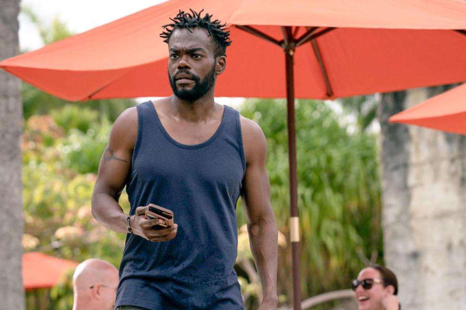 William Jackson Harper as Noah, holding his phone by a poolside area, in The Resort