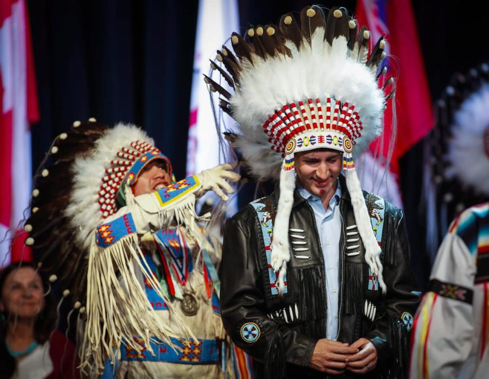 Prime Minister Justin Trudeau has his new headdress adjusted after receiving it at a ceremony while visiting the Tsuut'ina First Nation near Calgary, Alta., Friday, March 4, 2016. THE CANADIAN PRESS/Jeff McIntosh