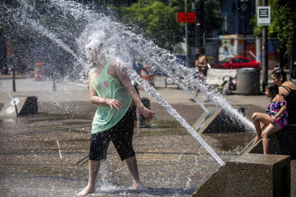 While Portland reached a record temperature of over 110 degrees Sunday, June 27, 2021 people gathered at Salmon Street Springs water fountain in Portland to cool off. (Mark Graves/The Oregonian via AP)