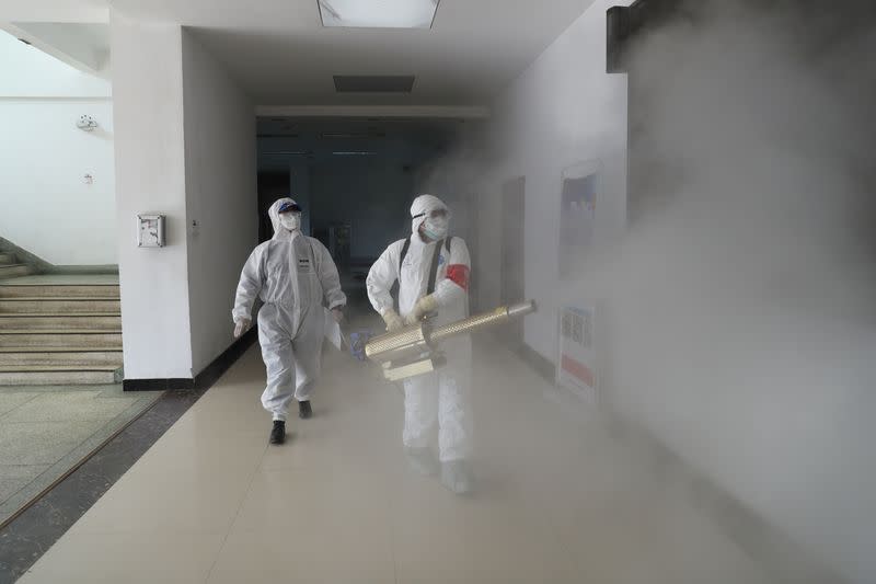 Volunteers in protective suits disinfect a residential compound in Wuhan