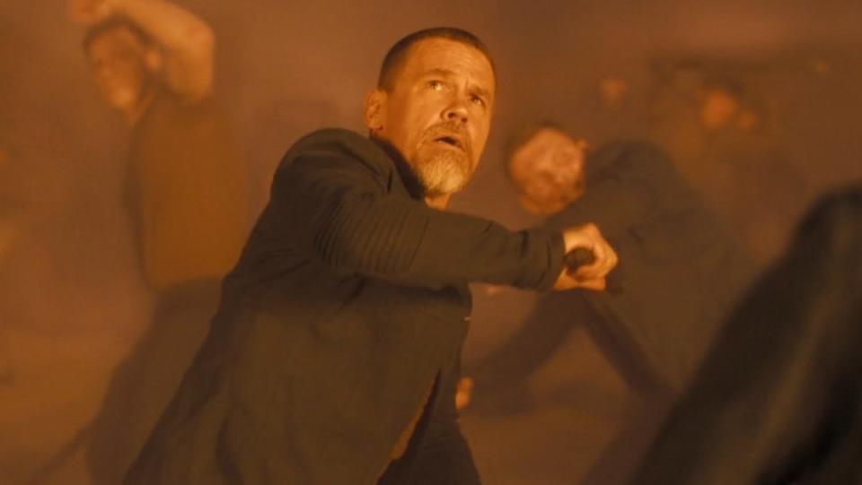 Gurney Halleck with a weapon recoils from a large orange blast during an attack in Dune