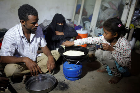 Yousef Mohammed (L), who has been displaced from the Red Sea port city of Hodeidah, looks at his daughter as she prepares food in a shelter in Sanaa, Yemen November 1, 2018. Picture taken November 1, 2018. REUTERS/Mohamed al-Sayaghi