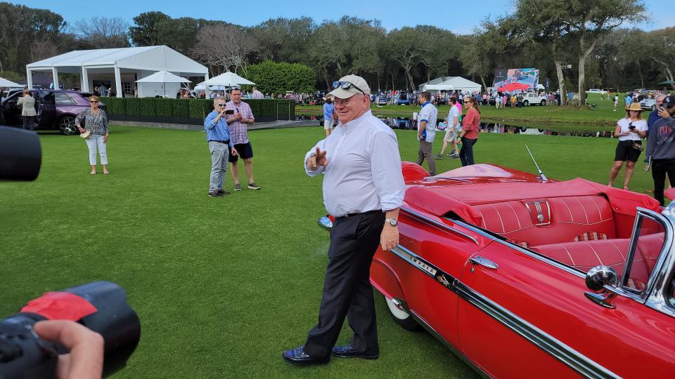 Chip Ganassi waves at fans and photographers after entering the show field in a 1959 Chevrolet Impala Convertible.