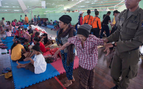 An evacuated villager from locations near the summit of Mount Agung, an active volcano which is showing increased seismic activity, is helped at a temporary shelter in Klungkung - Credit: REUTERS/ANTARA FOTO