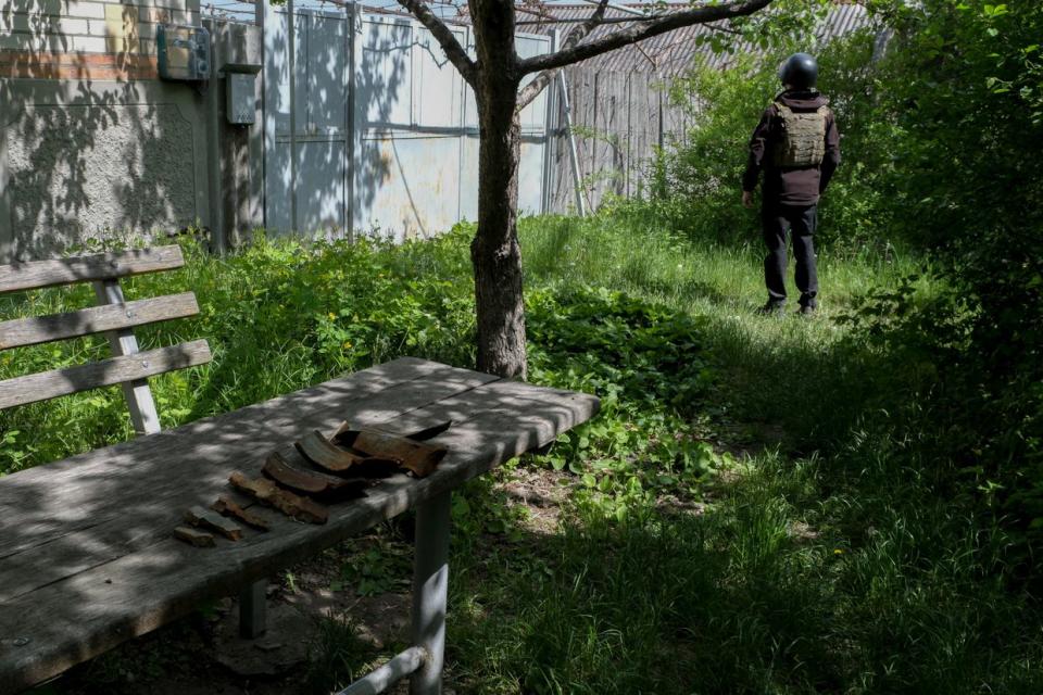 A police officer listens for Russian drones as shrapnel from aerial bombs lie on a table in Vovchansk, Kharkiv Oblast, on May 11, 2024. (Francis Farrell/The Kyiv Independent)