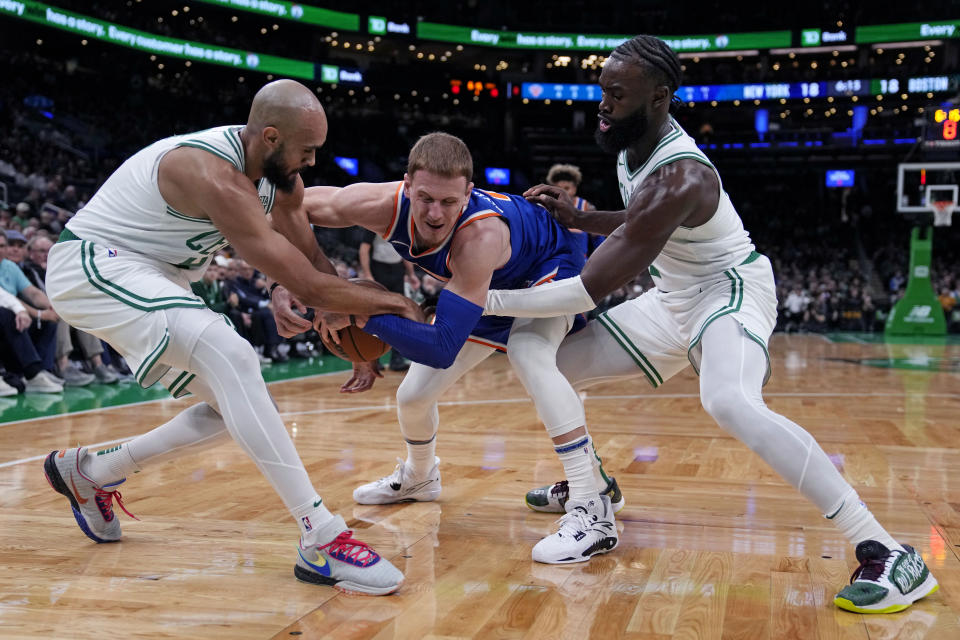 New York Knicks guard Donte DiVincenzo, center, is trapped by Boston Celtics' Derrick White, left, and Jaylen Brown during the first half of a preseason NBA basketball game, Tuesday, Oct. 17, 2023, in Boston. (AP Photo/Charles Krupa)