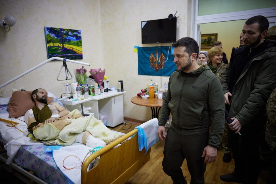 In this handout picture released and taken by Ukrainian Presidency Press Office on March 13, 2022, Ukrainian President Volodymyr Zelensky (2ndR) speaks to an injured man laying on a bed during a visit at a military hospital following fightings in the Kyiv region. (UKRAINIAN PRESIDENTIAL PRESS SER)