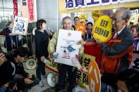 Demonstrators hold a placard showing a portrait of Hong Kong chief executive Leung Chun-ying as they protest prior to his his policy address on January 16, 2013. Hong Kong's Beijing-backed leader has unveiled a raft of populist policies with an emphasis on tackling the city's housing crisis, as he aimed to hush critics' repeated calls to step down