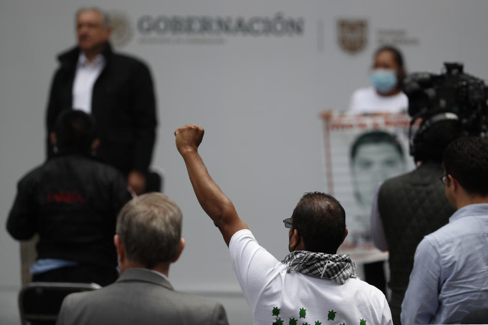 A man raises his fist as family members of 43 missing students from the Rural Normal School of Ayotzinapa chant for justice, following an event with Mexico's President Andres Manuel Lopez Obrador, top left, at the National Palace in Mexico City, on the sixth anniversary of the students disappearance, Saturday, Sept. 26, 2020.(AP Photo/Rebecca Blackwell)