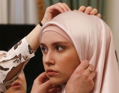 A model gets assistance while preparing backstage before a show of the Firdaws fashion house led by Aishat Kadyrova, daughter of the Chechen Republic head Ramzan Kadyrov, at the Mercedes-Benz Fashion Week Russia in Moscow, Russia, March 17, 2017. REUTERS/Sergei Karpukhin