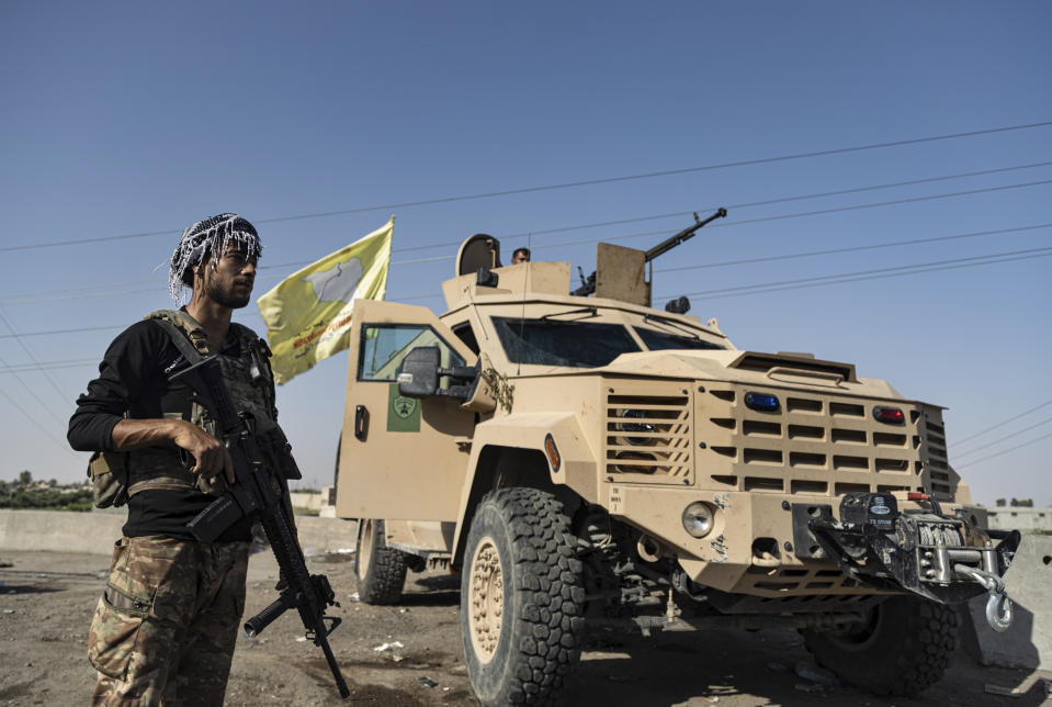 A U.S.-backed Syrian Democratic Forces (SDF) fighter stands next an armored vehicle, at al-Sabha town in the eastern countryside of Deir el-Zour, Syria, Monday, Sept. 4, 2023. Weeklong clashes between rival U.S.-backed militias in eastern Syria, where hundreds of American troops are deployed, point to dangerous seams in a coalition that has kept on a lid on the defeated Islamic State group for years. (AP Photo/Baderkhan Ahmad)