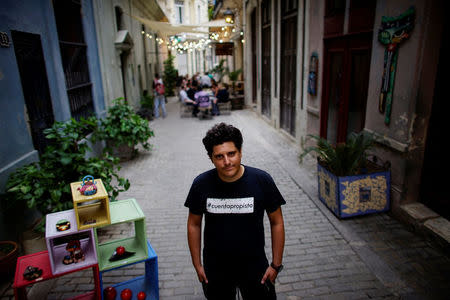 Self-employed Camilo Condis, 32, poses for a photo next to the restaurant where he works in Havana, Cuba, March 21, 2018. The sign in his shirt reads in Spanish "Self-employed". REUTERS/Alexandre Meneghini