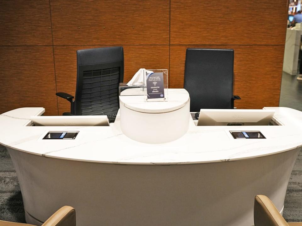 A white desk with black chairs and a sign with information about the Wifi