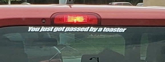 A decal on a Nissan Cube that says you just got passed by a toaster